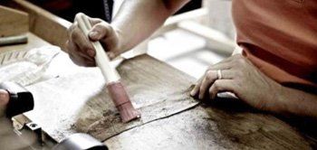Una persona sta dipingendo un pezzo di legno con un pennello.