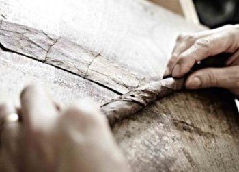 Una persona sta tagliando un pezzo di legno su un tavolo.