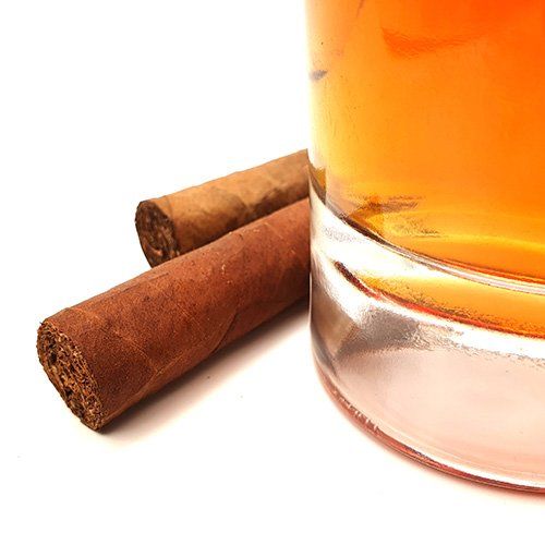 Due sigari accanto a un bicchiere di whisky
