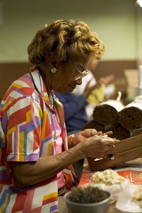Una donna è seduta a un tavolo e sta preparando sigari.