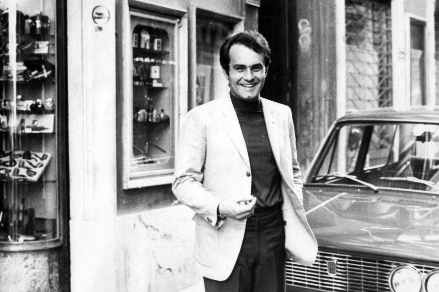 Un uomo è in piedi davanti a un'auto in una foto in bianco e nero.