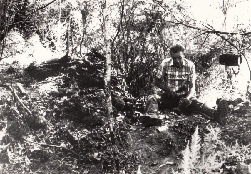 Una foto in bianco e nero di un uomo seduto nel bosco