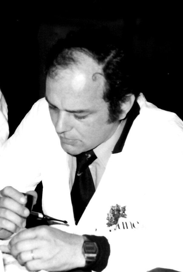 Un uomo che indossa un camice bianco e una cravatta sta lavorando a qualcosa