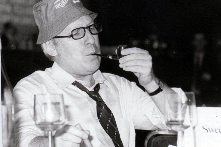Un uomo che indossa un cappello e una cravatta sta bevendo da un bicchiere