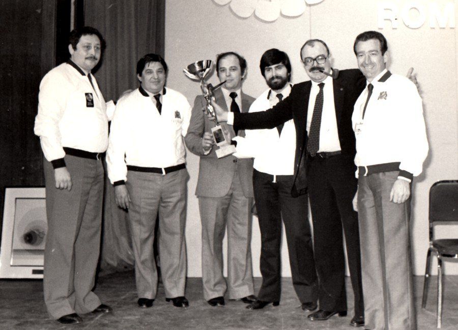 Un gruppo di uomini posa per una foto e uno di loro tiene in mano un trofeo