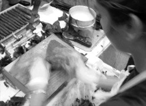 Una foto in bianco e nero di una donna che prepara il cibo