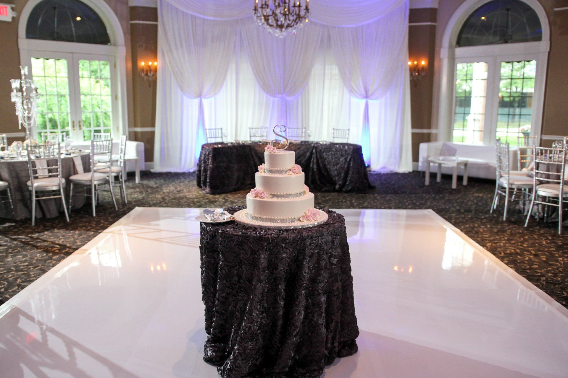 A wedding cake is sitting on top of a table on a dance floor.