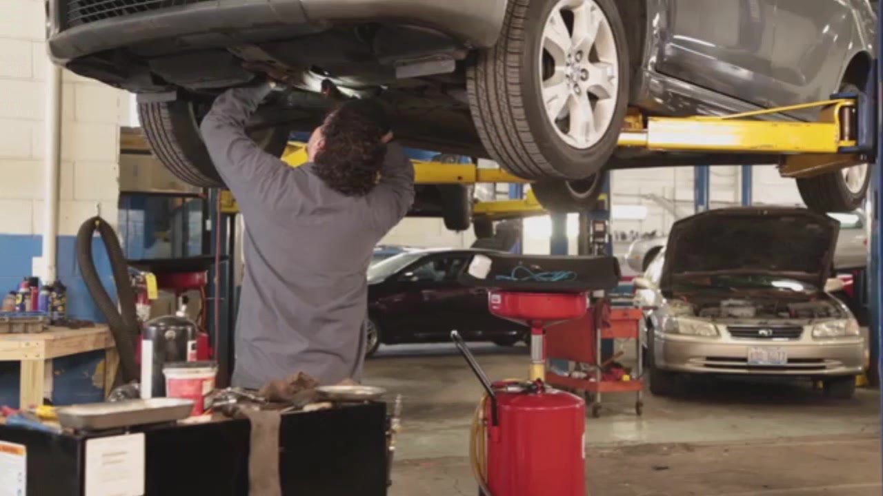 A man is working under a car on a lift in a garage.