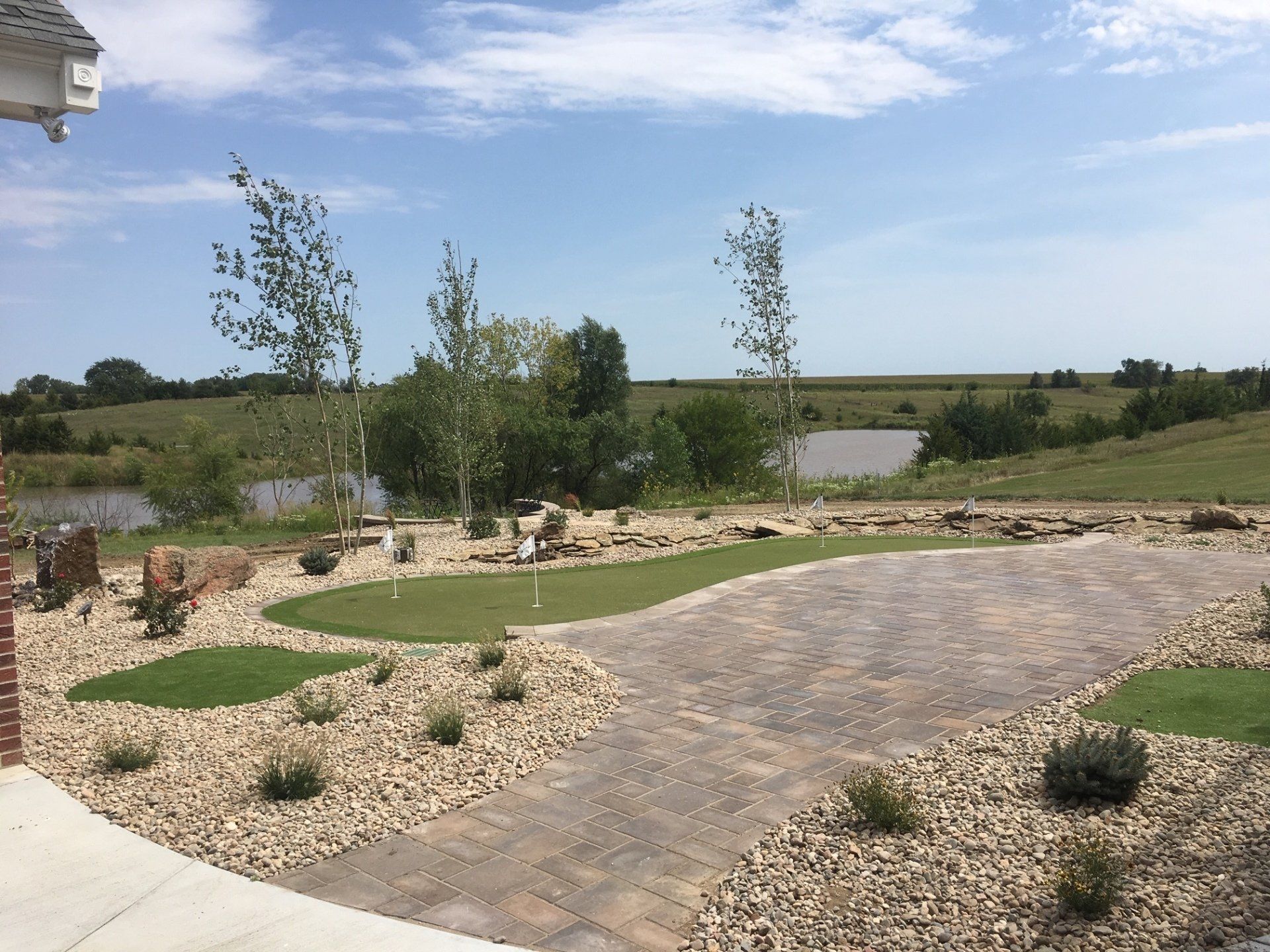 A patio with a green lawn and a lake in the background