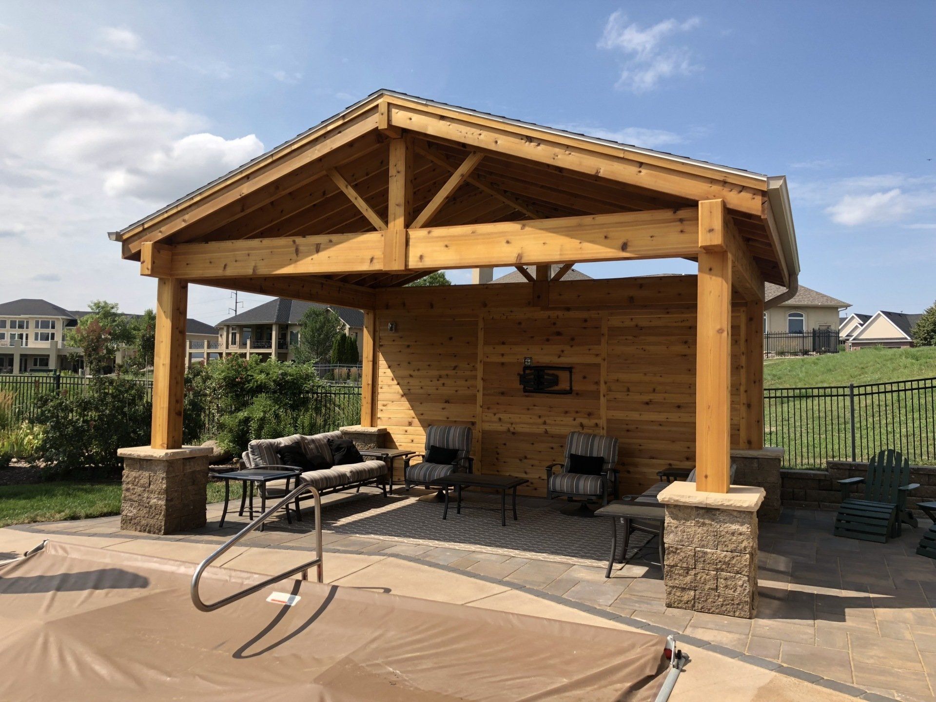 A wooden pavilion is sitting next to a swimming pool.