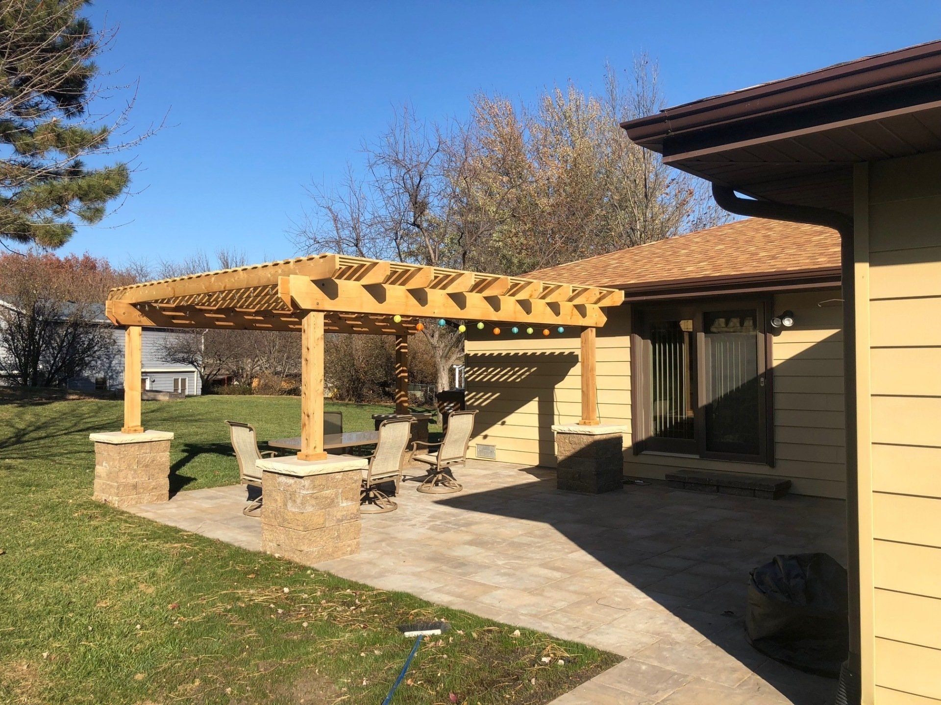 A house with a pergola and a patio in front of it.