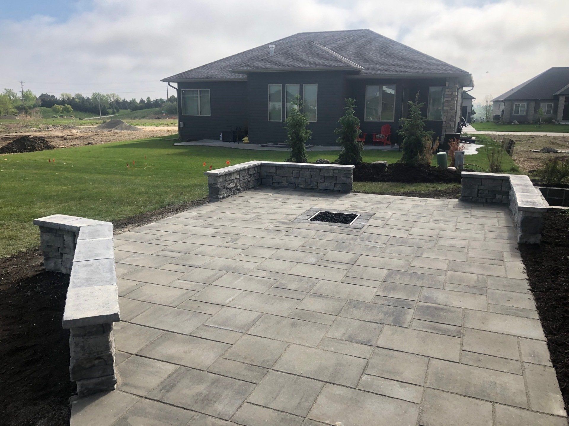 A patio with a fire pit and benches in front of a house.