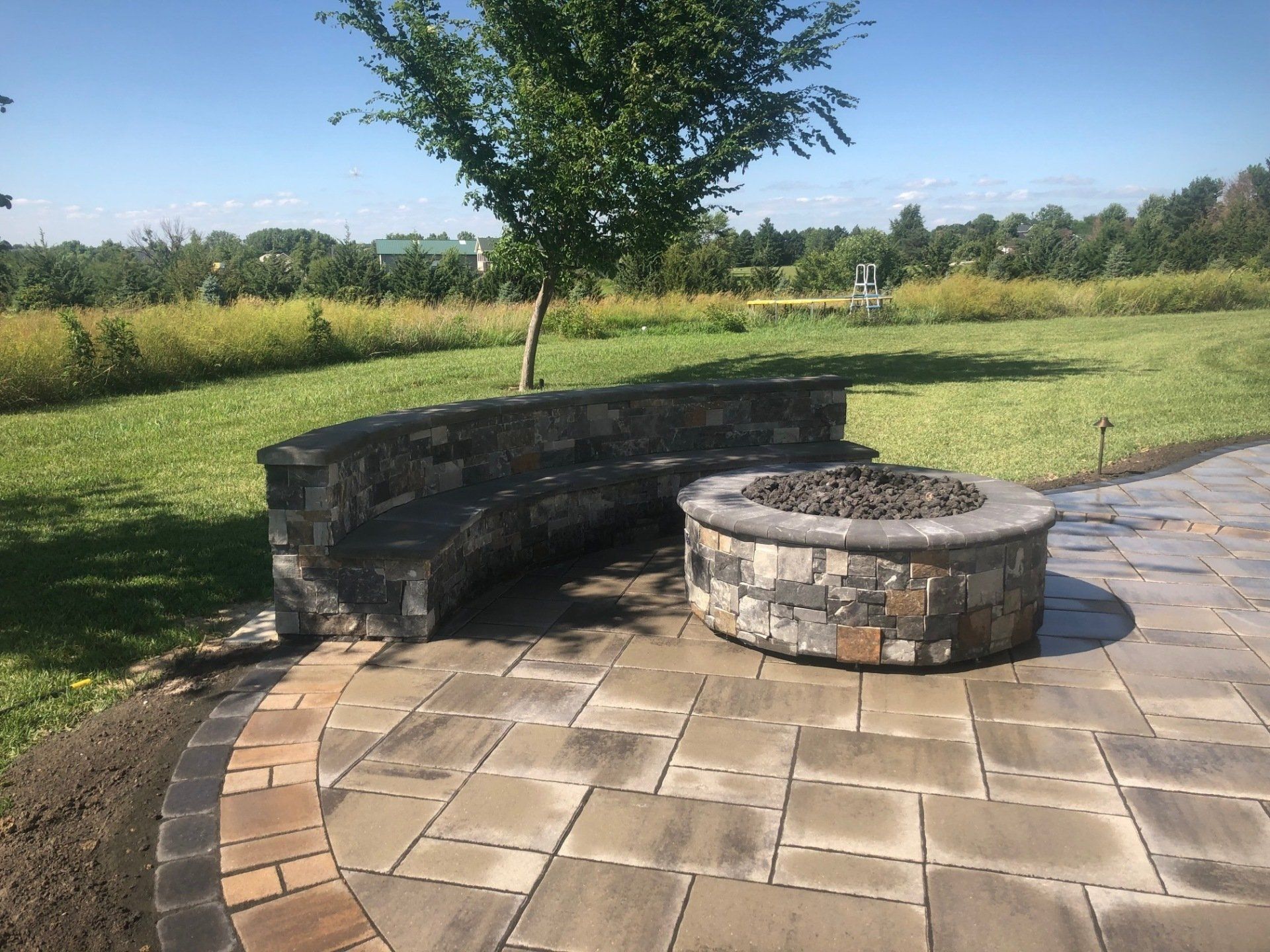 A fire pit is sitting on a patio next to a stone wall.