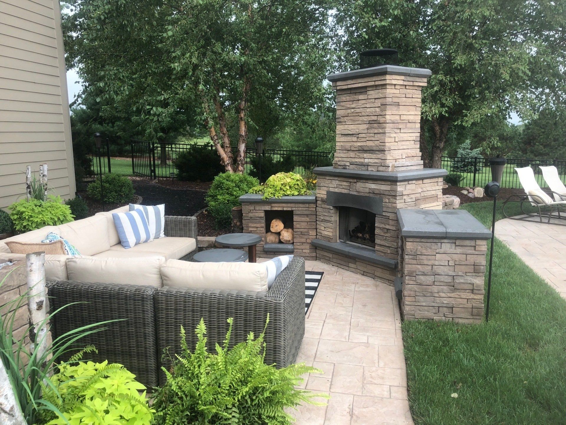 A patio with a fireplace and a couch and chairs