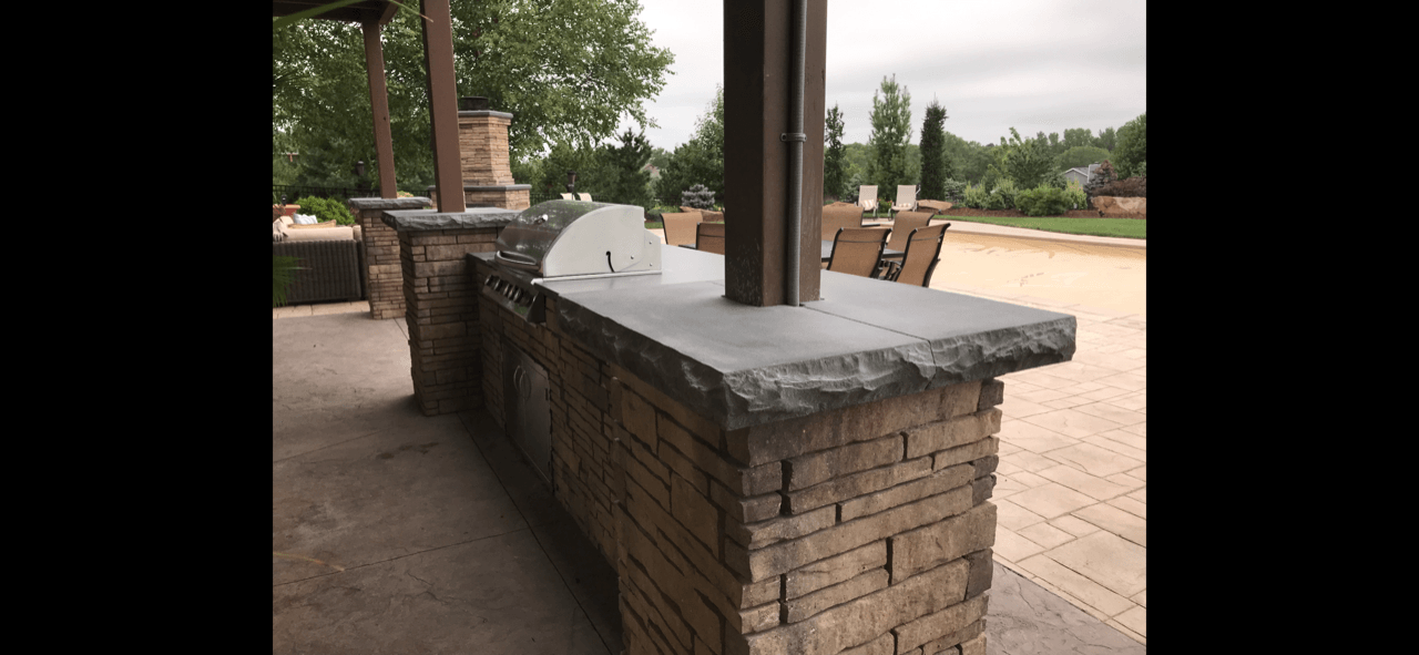 A brick bar with a grill on it is sitting on top of a brick patio.