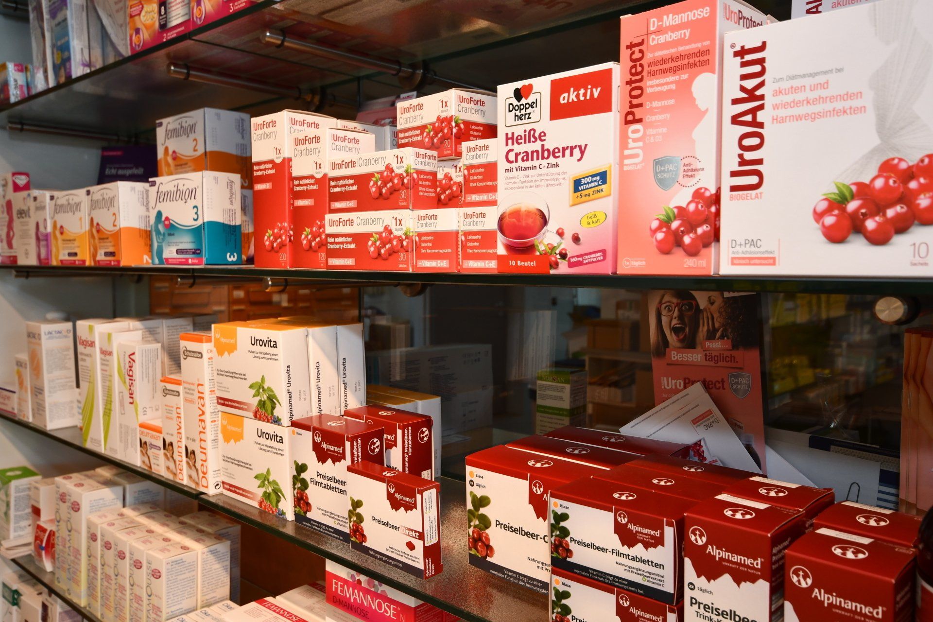 Regale in einer Apotheke, gefüllt mit verschiedenen Cranberry-Nahrungsergänzungsmitteln in rot-weißer Verpackung.