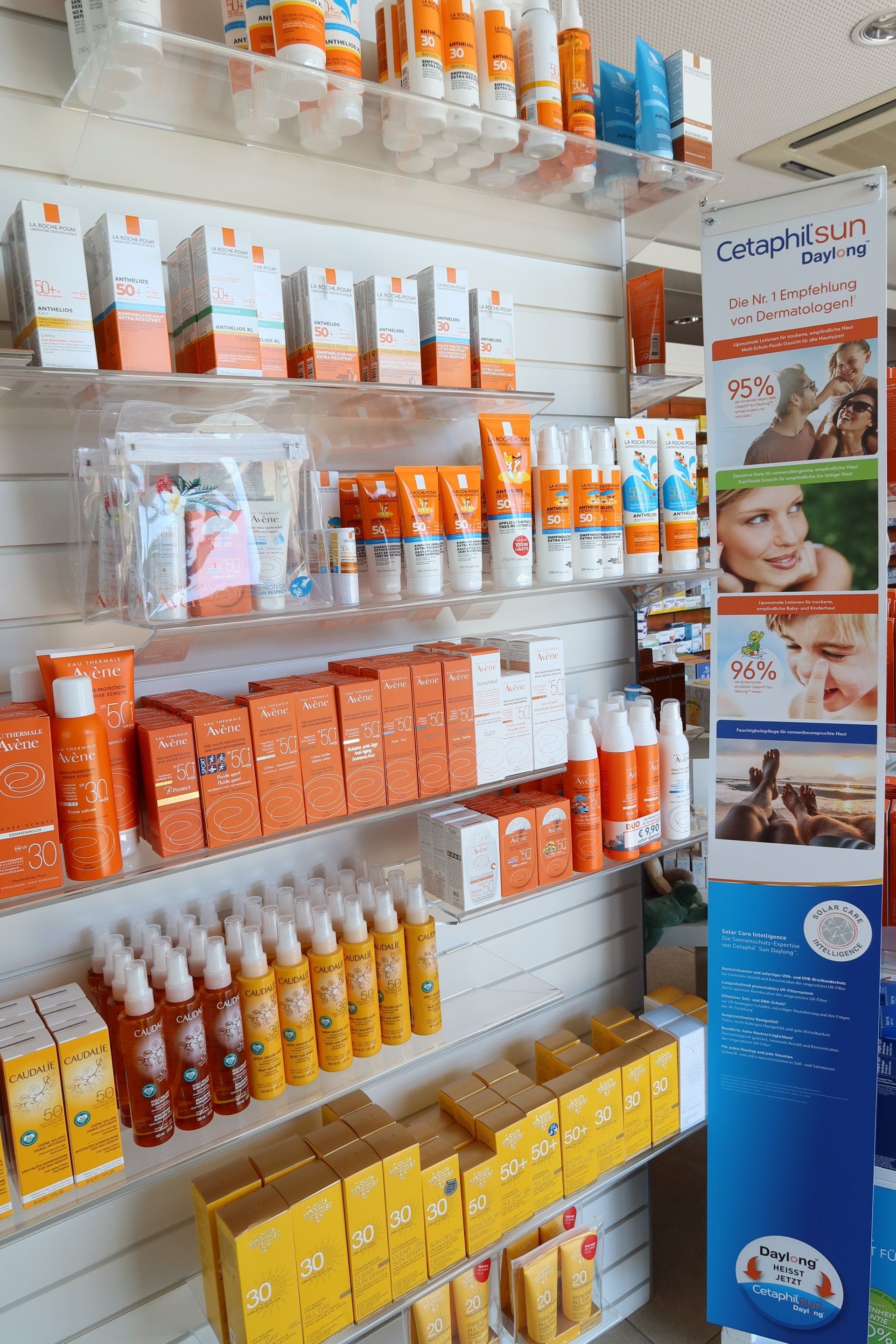 In einer Apothekenumgebung befinden sich Regale voller verschiedener orangefarbener und gelber Hautpflegeprodukte.