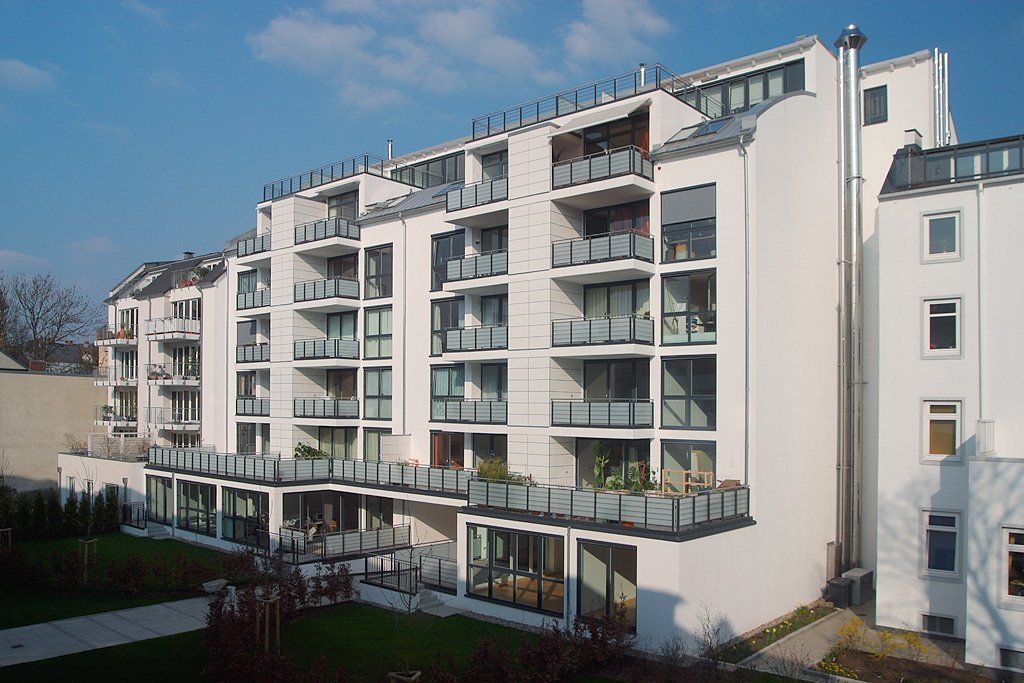 Mehrfamilienhaus mit Balkonen und großen Fenstern an einem sonnigen Tag