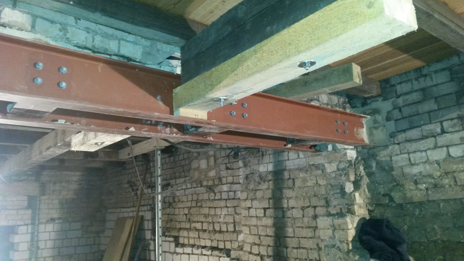 Rustikales Interieur mit freiliegenden Ziegelwänden und großen Metallträgern, die die Decke stützen.
