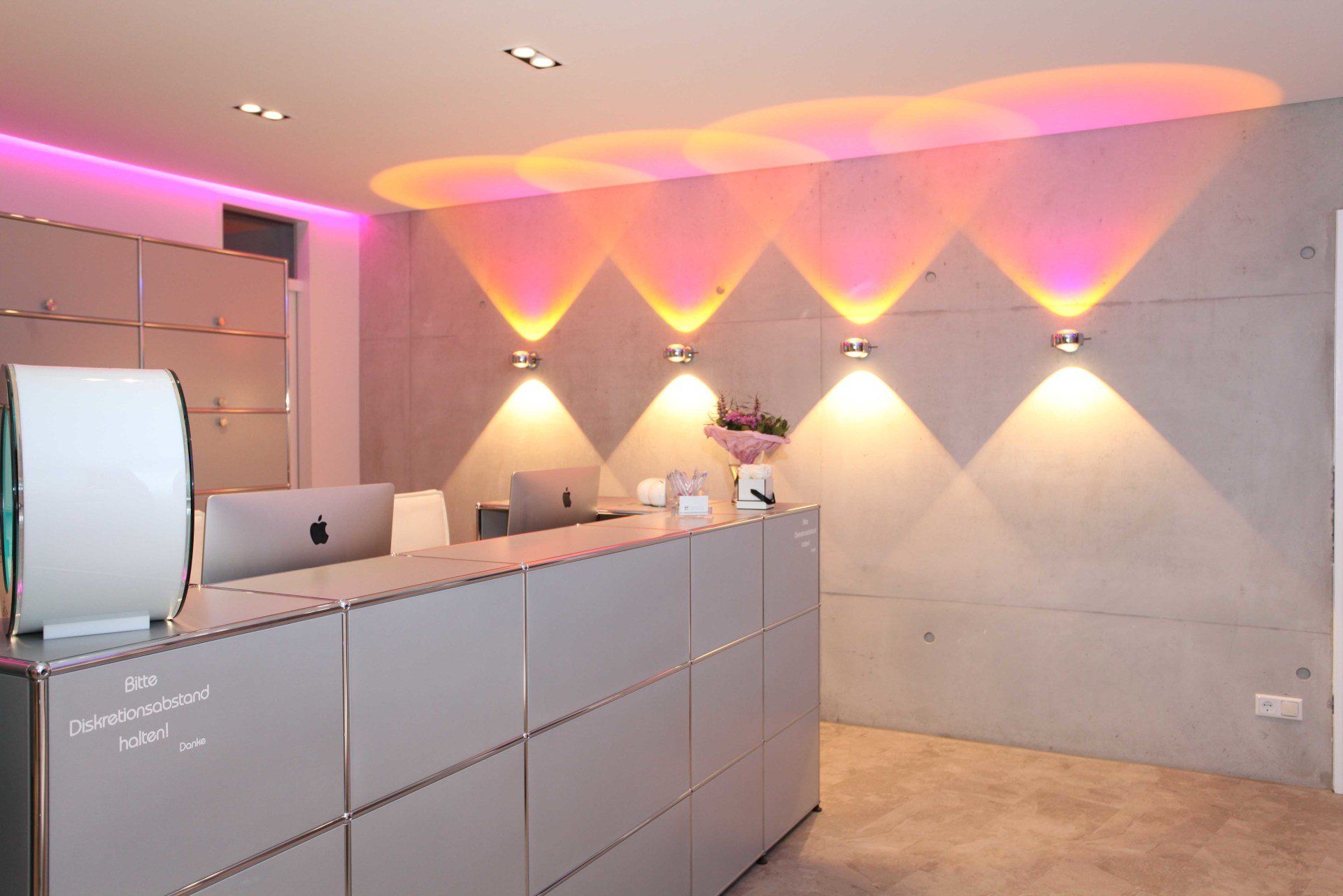 Moderner Empfangsbereich mit rosa und orangefarbener Beleuchtung in einer minimalistischen Lobby