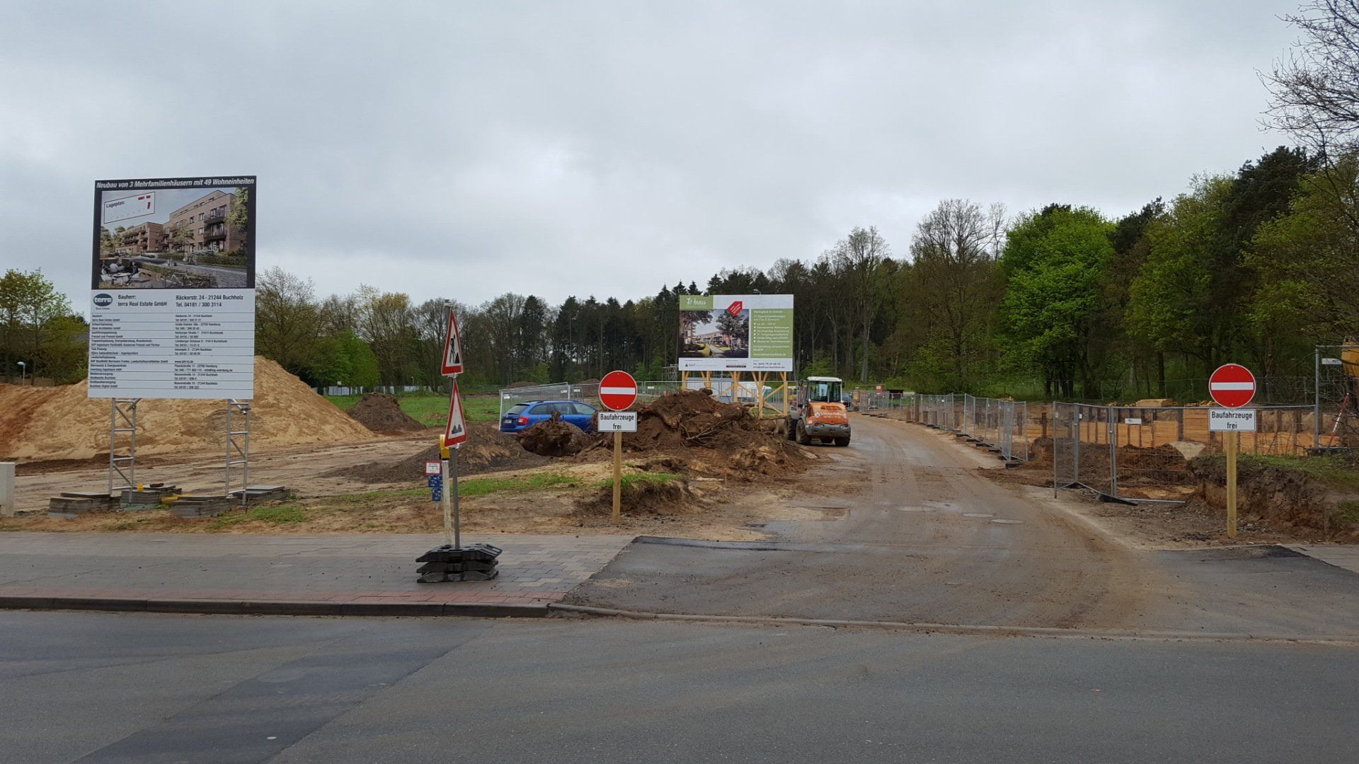 Straßenarbeiten an einer Kreuzung mit Erdhaufen, Baustellenschildern und einer teilweise blockierten Straße