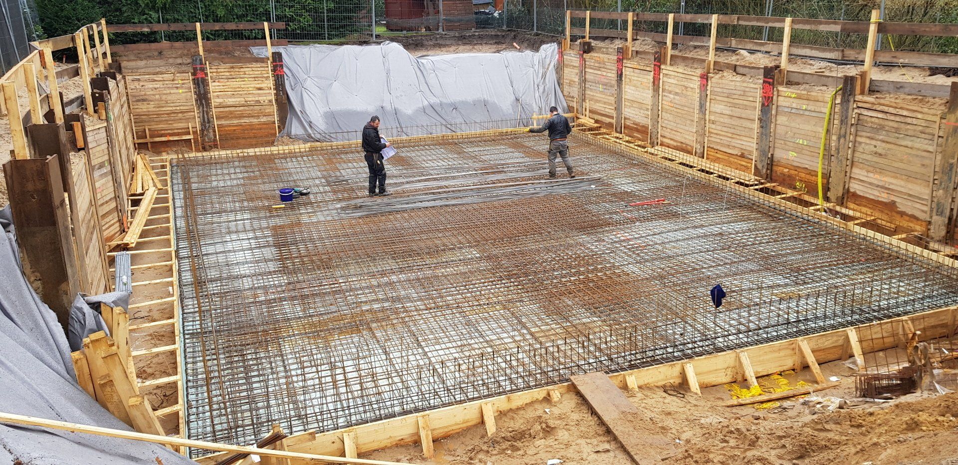 Arbeiter gießen Beton für ein Gebäudefundament auf einer Baustelle.