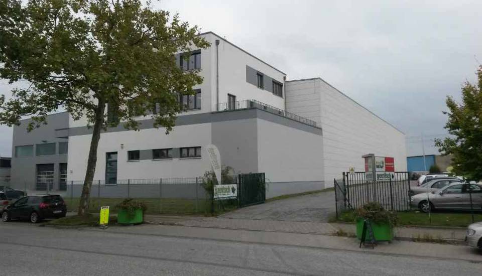 Modernes weißes Industriegebäude mit geparkten Autos und Topfpflanzen entlang einer Straße