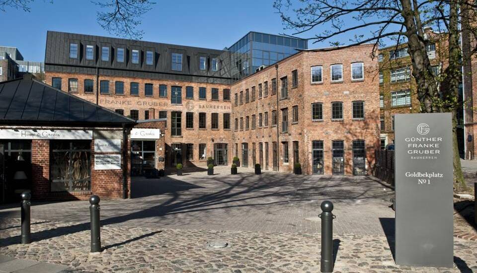 Innenhof eines Backsteinbürogebäudes mit Kopfsteinpflaster und einem Schild im Vordergrund