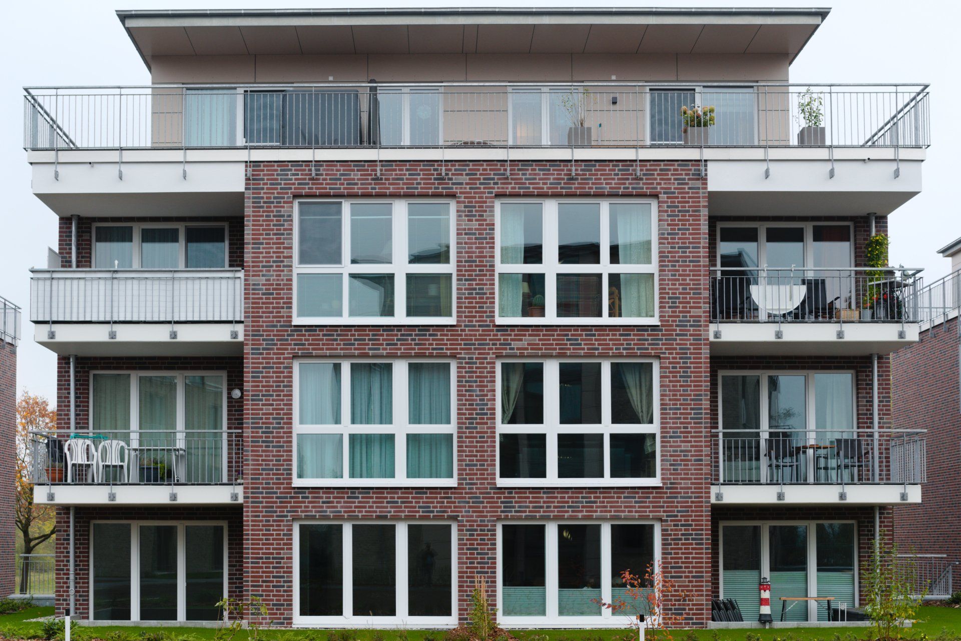 Moderne Wohnhausfassade aus roten Ziegeln und grauen Balkonen unter einem bedeckten Himmel