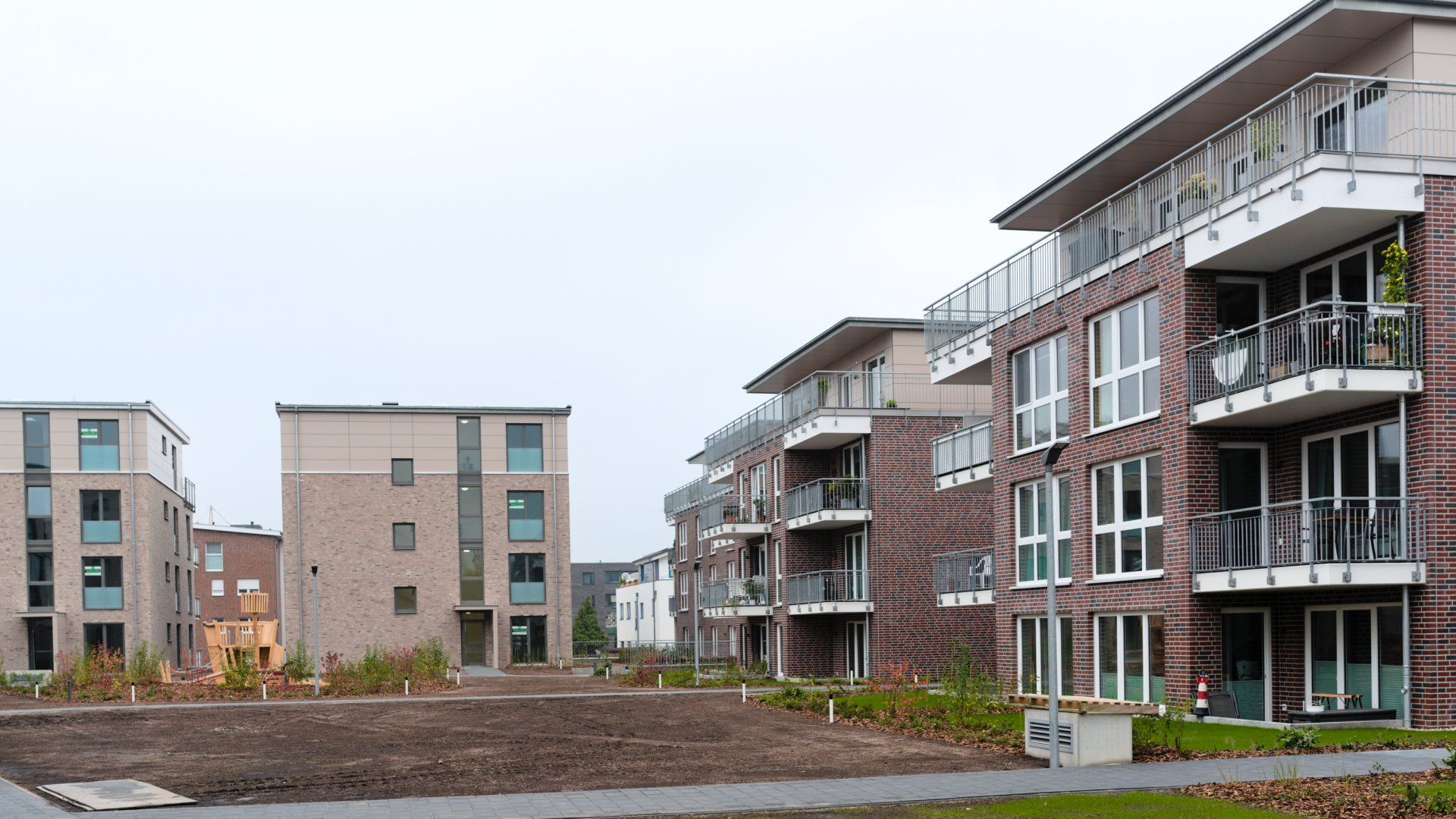 Moderne Apartmentgebäude umgeben ein unbebautes Grundstück unter einem bedeckten Himmel