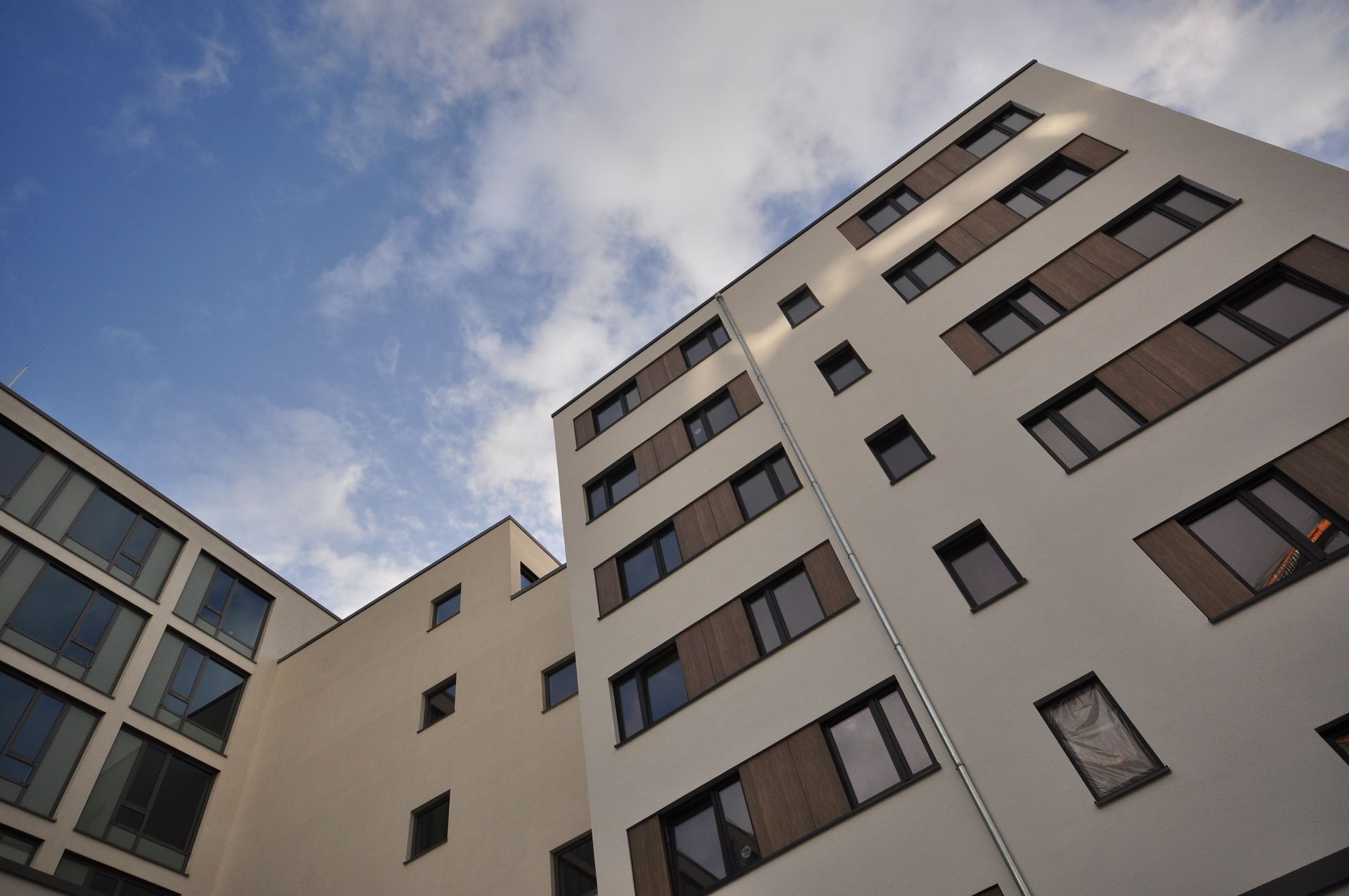 Ansicht von unten auf moderne Wohnhäuser vor blauem Himmel mit Wolken