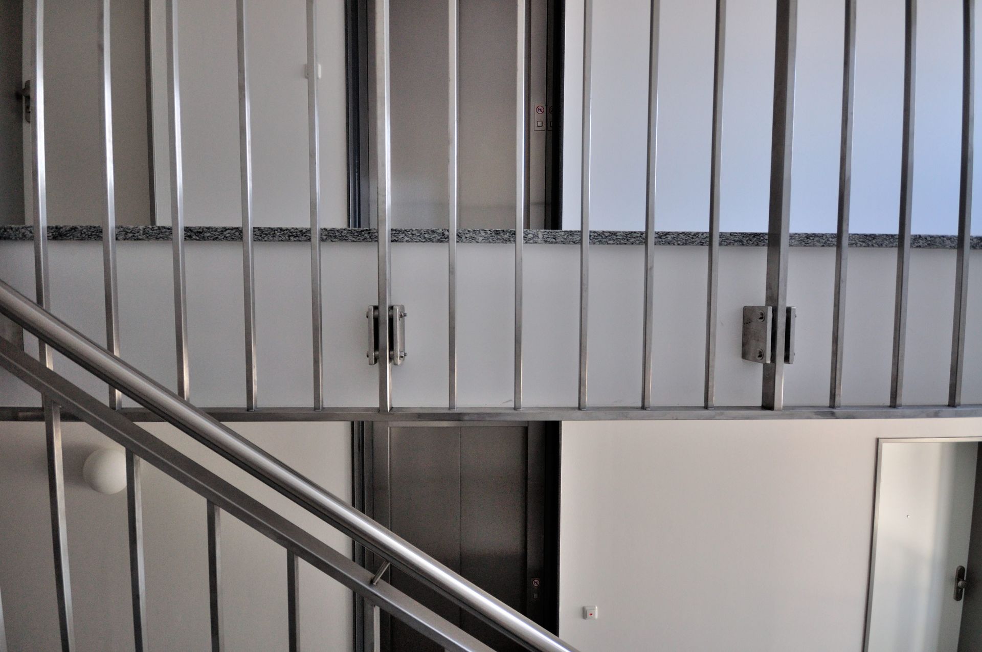 Innentreppenhaus mit Metallgeländer und einer Wand aus vertikalen weißen Paneelen.