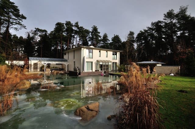 Haus neben einem Teich mit Schilf, Felsen und Bäumen in einem angelegten Garten