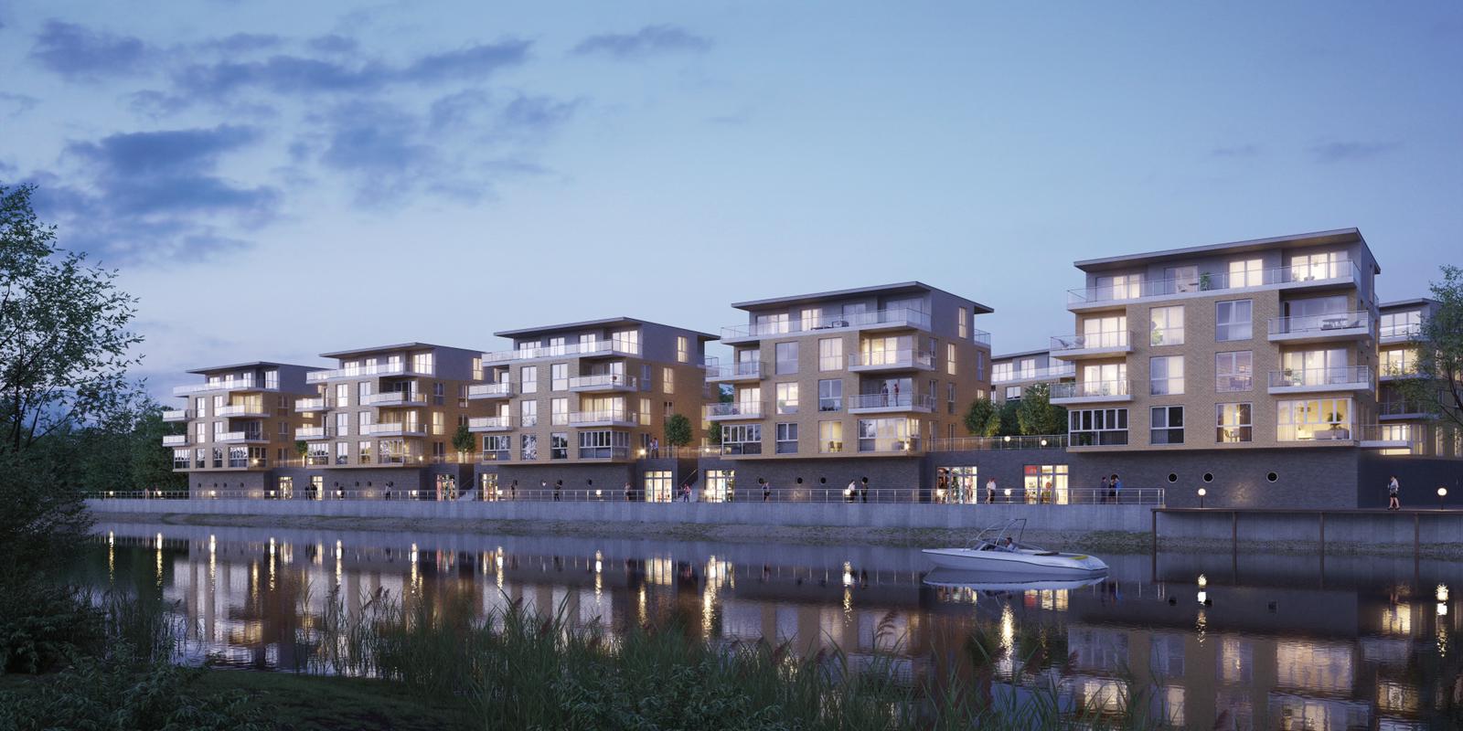 Moderne Wohnhäuser am Flussufer in der Abenddämmerung, deren beleuchtete Fenster sich im ruhigen Wasser spiegeln.