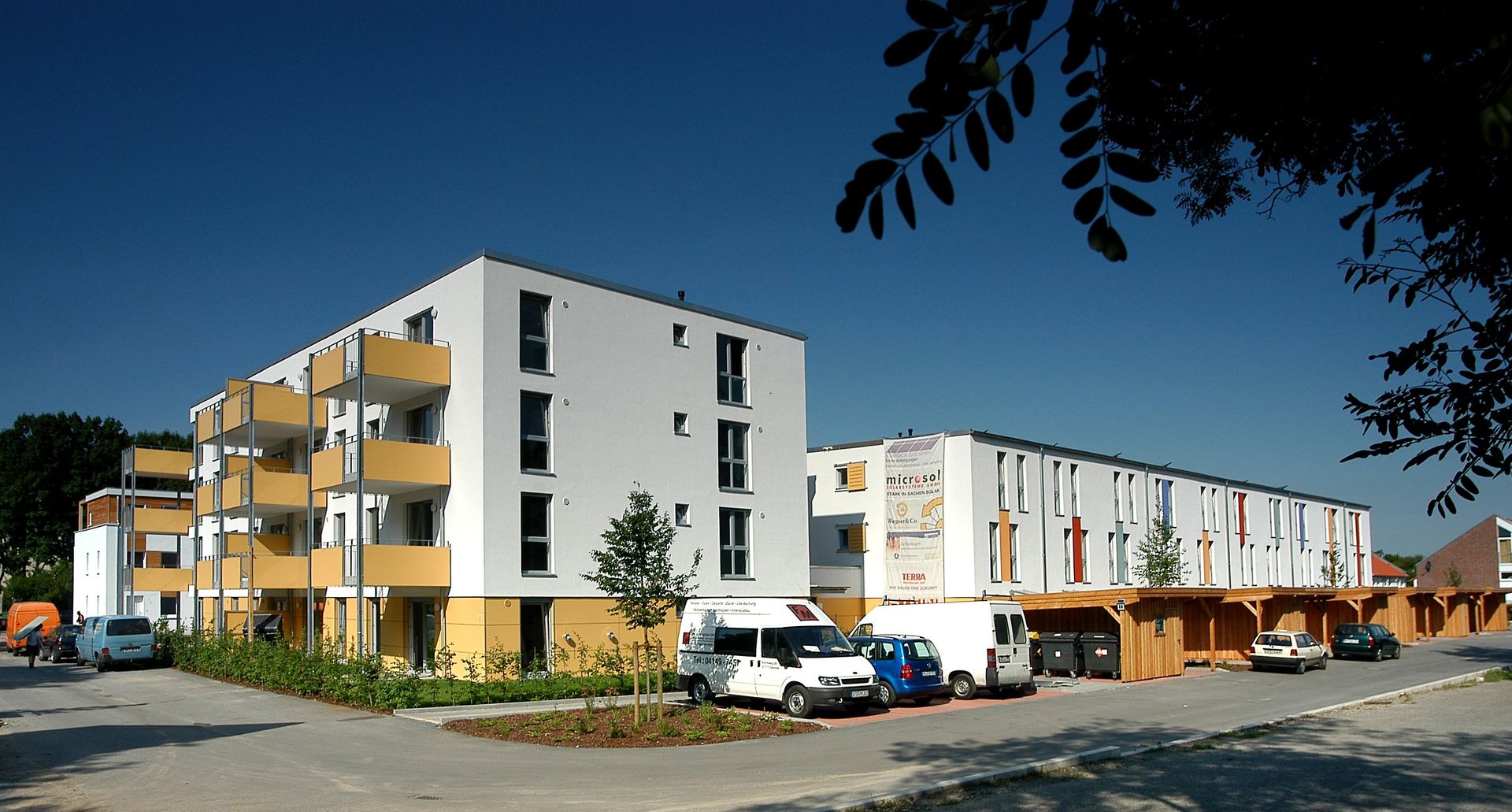 Modernes Wohnhaus mit Balkonen und Geschäften im Erdgeschoss an einem sonnigen Tag