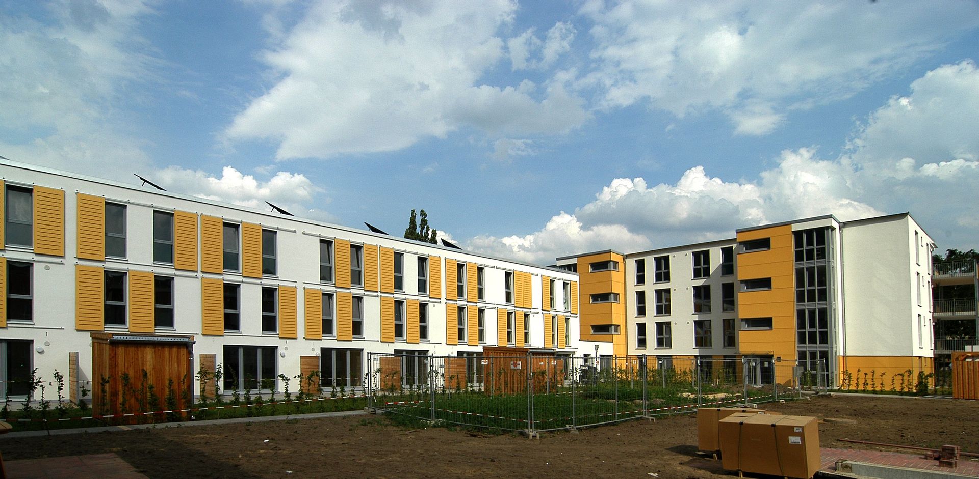 Moderne Wohnhäuser mit gelb-weißen Fassaden unter einem bewölkten Himmel