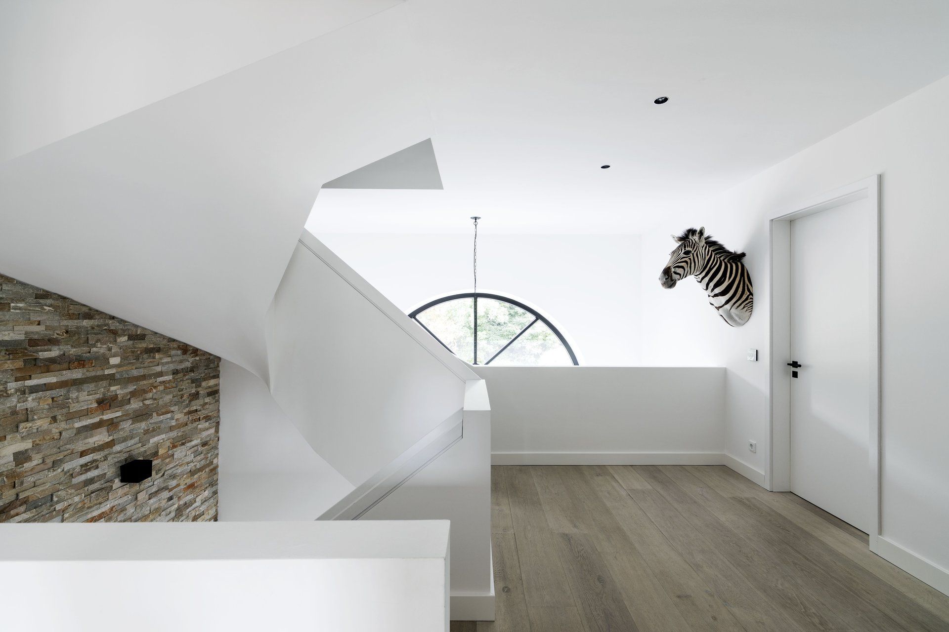 Moderner weißer Flur mit Holzboden, Steinwand, Treppe und Zebra-Kopf-Wandbild