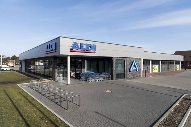 Außenansicht des ALDI-Supermarkts mit Fahrradständern und Parkplatz an einem sonnigen Tag
