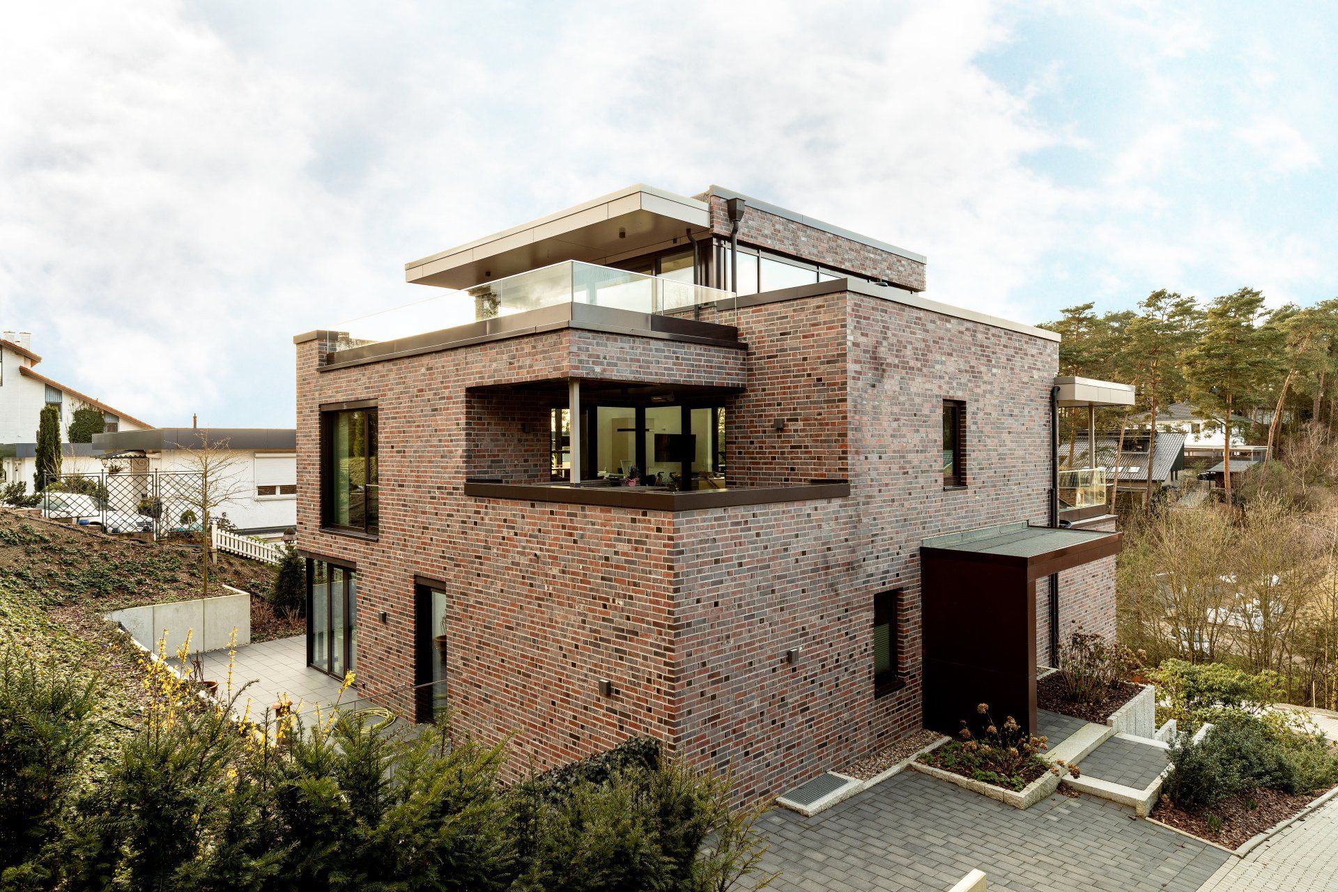 Modernes zweistöckiges Backsteinhaus mit Dachterrasse und großen Fenstern in einer gepflegten Wohngegend
