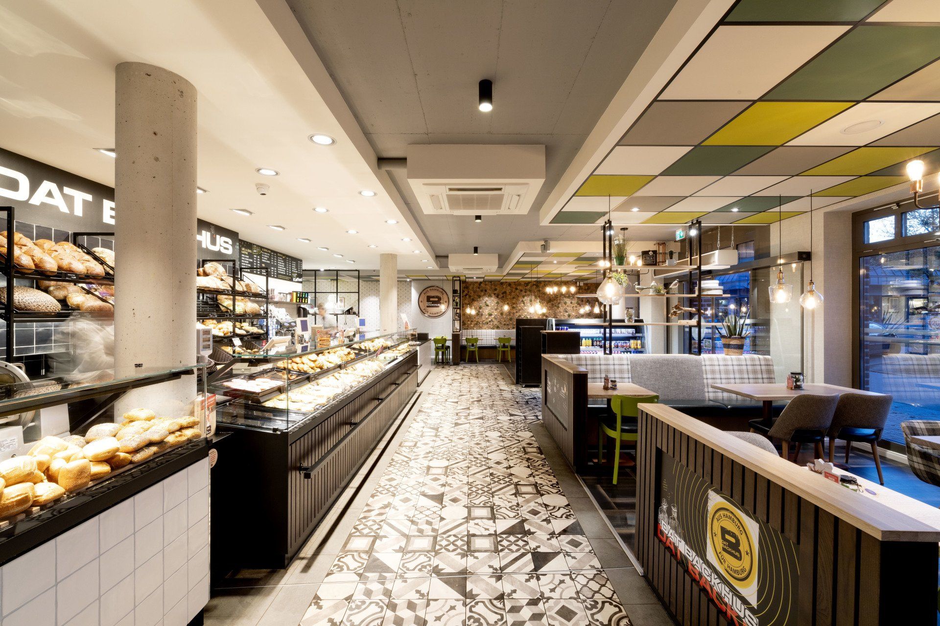 Modernes Buffetrestaurant-Interieur mit gemustertem Boden, Thekenauslagen und Sitzbereich