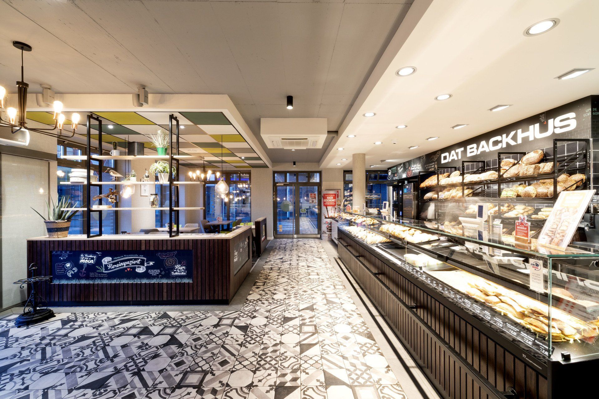 Helle Bäckereitheke mit Gebäck unter Glasvitrinen und gemustertem schwarz-weißen Boden in einem modernen Laden