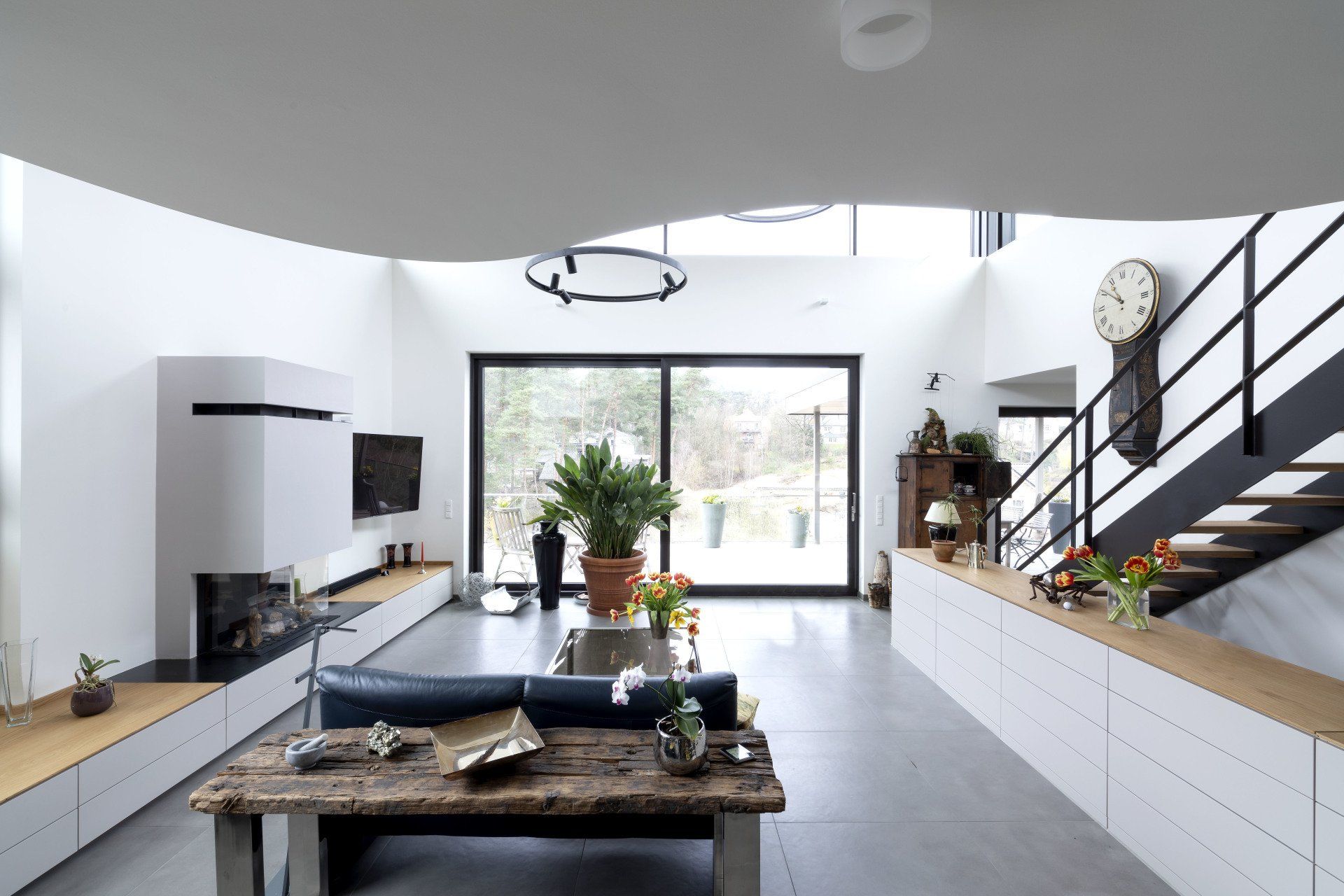 Modernes, offenes Wohnzimmer mit Kücheninsel, großem Fenster und Treppe