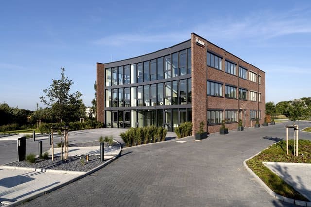 Modernes Backsteinbürogebäude mit großen Glasfenstern und gepflasterter Zufahrt