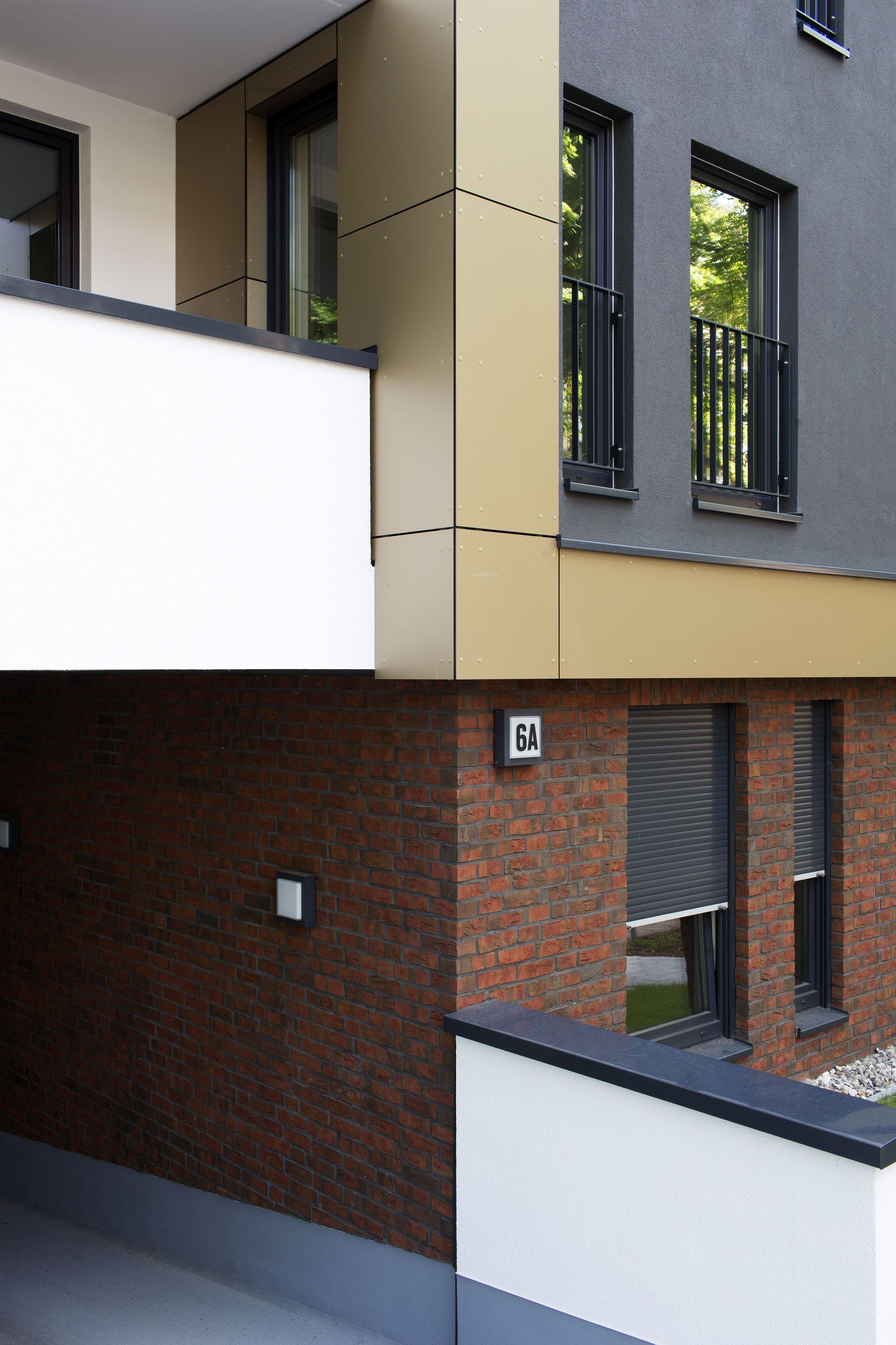 Fassade eines modernen Mehrfamilienhauses mit grauen, weißen und gemauerten Wänden und Balkonen