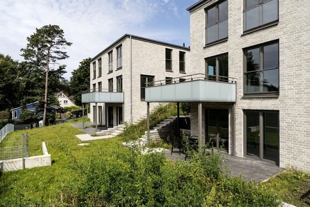 Modernes Apartmentgebäude mit Steinfassade, Balkonen und einem begrünten Innenhof