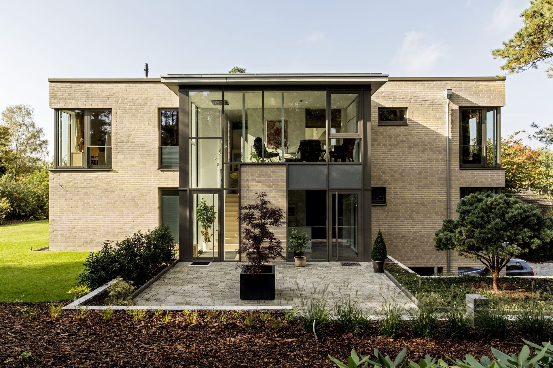 Modernes zweistöckiges Backsteinhaus mit großem Glaseingang und angelegtem Vorgarten