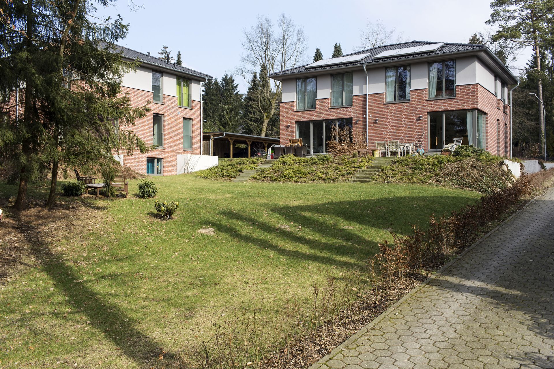 Backstein-Wohnhäuser umgeben einen begrünten Innenhof mit gepflastertem Weg und Bäumen.