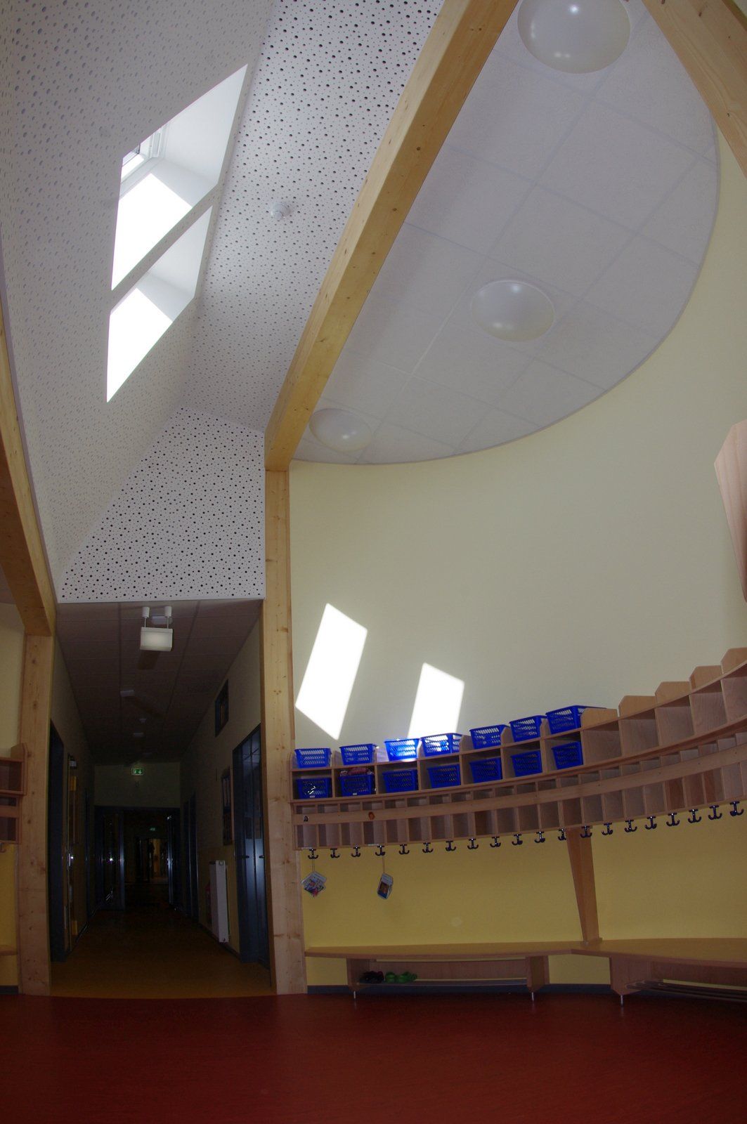Modernes Zimmer mit schrägen Fenstern, gewölbter Decke und einer Wand aus kleinen blauen Paravents über Holzregalen.