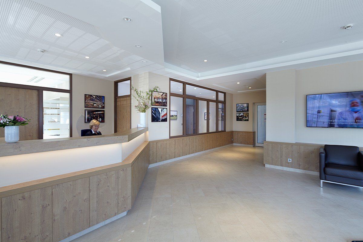 Leere, moderne Lobby mit Rezeption, beigefarbenem Teppichboden, Holzvertäfelung und an der Wand montiertem Fernseher