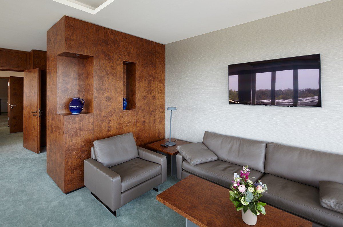 Modernes Wohnzimmer mit grauem Sofa und Sessel, Akzentwand aus Holz, Couchtisch und Wandbildern.